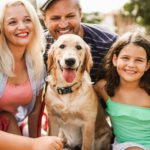 Happy family having fun with children and their dog outdoor summer time - Main focus on dog face