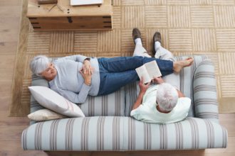 Poetry is the language of love...A senior man reading to his wife as she she lies on the couch.